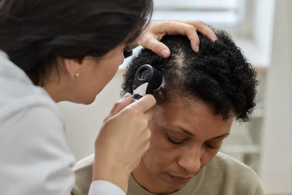 A clinician examining an adult patient’s scalp during a consultation